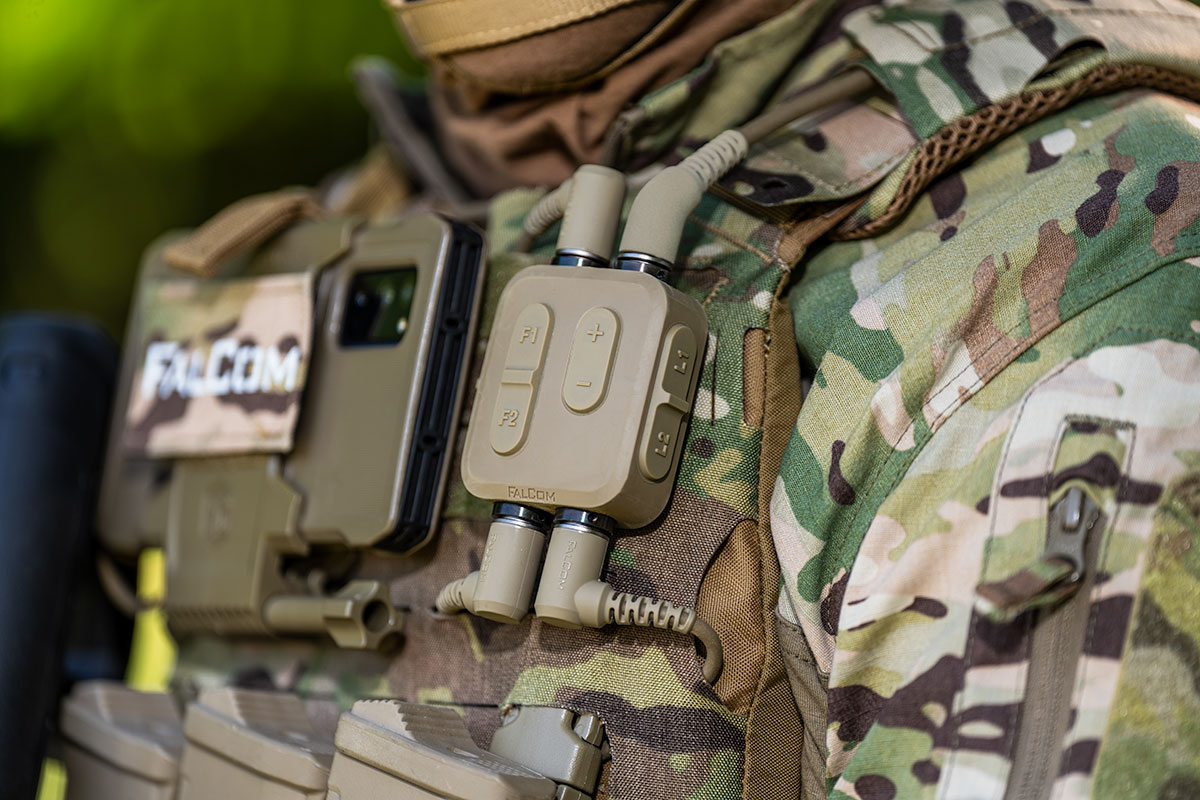 Up close image of FalCom Hub in color tan, attached to combat uniform next to EUD.